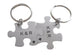 Two silver puzzle piece keychains with 'K&R' initials on a light gray background