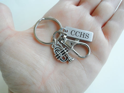 A silver-toned metal keychain with a split ring, a small trumpet charm, a lobster clasp, and a rectangular tag engraved with the name 'Steve', shown on a plain light background.